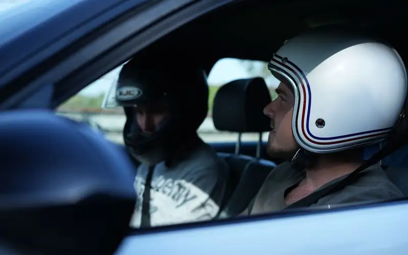 Un passager casqué à côté de son pilote, dans l'habitacle d'une voiture de sport
